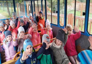 dzieci siedzą na ławeczkach w pociągu