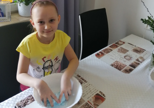 dziewczynka w żółtej bluzce, w białej misce ugniata ciasto