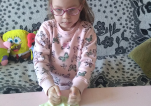 dziewczynka odciska pięści na zielonym cieście