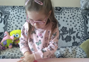 dziewczynka ugniata różową masę na stole w pokoju