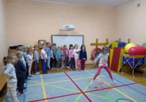 dzieci stoją w rzędzie i czekają w kolejce do ćwiczenia - skoki po kołach