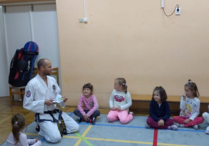 instruktor klęczy z dziećmi w kole na macie w paski