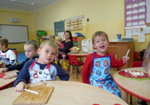 dzieci siedzą przy stolikach z deskami do krojenia