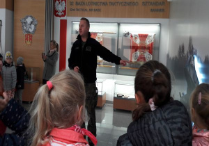dzieci słuchają żołnierza opowiadającego o historii bazy lotnictwa