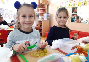 dziewczynki kroją plastikowymi, zielonymi nożami