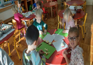 dzieci kroją jabłka na zielonych deskach