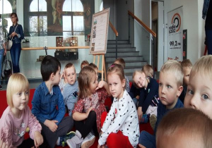 dzieci z panią siedzą w grupce na holu w teatrze