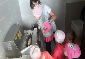 maszyna kroi chleb i pokazuje dzieciom - podnosi dziewczynkę