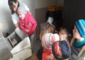 maszyna kroi chleb a pani podnosi dziewczynkę nad nią aby zobaczyła