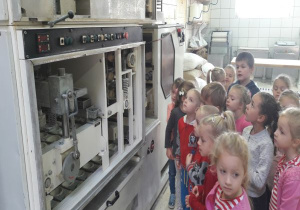 dzieci zaglądają maszynę do formowania pączków