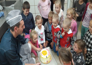 tata kuca i pokazuje dzieciom tort ze słoneczkiem