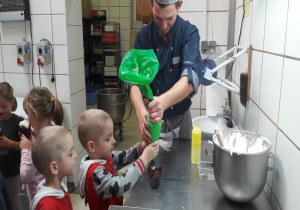 tata pomaga chłopcu i jego bratu ozdabiać mufinki bitą śmietaną