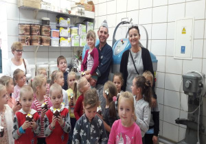 tata trzyma córkę, obok stoi nauczycielka a dzieci trzymają mufinki