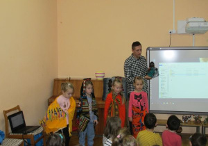 Mateusz pokazuje lalkę afrykańską a dziewczynki stoją ubrane w regionalne chusty
