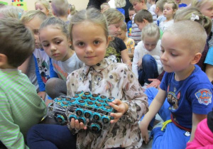 dziewczynka trzyma auto ozdobione niebieskimi kapslami