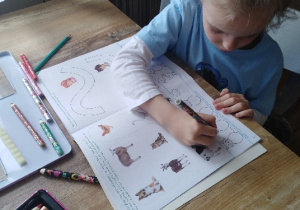 dziewczynka przy stole pracuje w książce