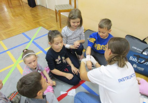 instruktorka bandażuje rękę dziewczynki