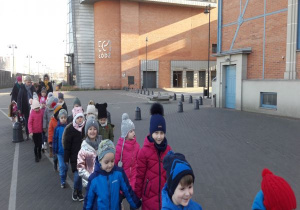 dzieci idą parami przed budynkiem planetarium w Łodzi