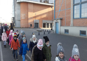 dzieci idą parami przed budynkiem planetarium w Łodzi