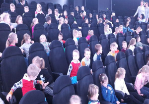 dzieci siedzą na fotelach w planetarium