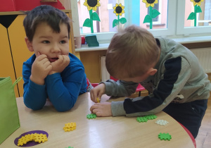 chłopcy bawią się przy stoliku klockami - małymi, kolorowymi kratkami