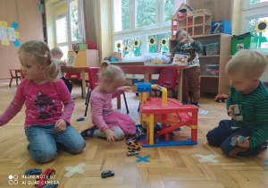 na podłodze dzieci bawią się garażem dla aut