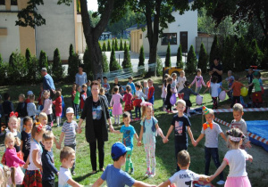 szystkie dzieci tańczą w grupowych kołach, trzymając balony i śpiewają piosenkę