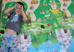 zmęczony chłopiec odpoczywa na macie i robi okulary przykładając dłonie do oczu
