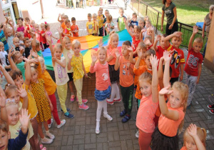 dzieci tworzą promienie słońca wg kolorów chusty i odpowiadających im kolorów ubrań