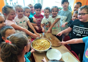 dzieci pokazują miskę z pokrojonymi na sałatkę owocami