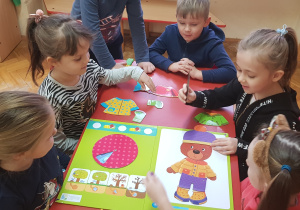dziewczynka zakłada misiowi czapkę