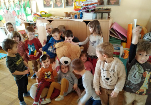 gr. IX - dzieci przytulają sie do wielkiej maskotki misia z każdej strony i pozują do zdjęcia