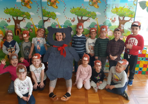 gr. III - zdjęcie grupowe dzieci w opaskach z głową misia i z nauczycielką w foto budce "szarego misia z czerwona kokardą"