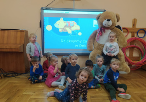 gr. II - zdjęcie grupowe z wielka maskotka misia przed tablicą multimedialną