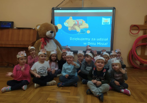 gr.VIII - zdjęcie grupowe z wielka maskotka misia przed tablicą multimedialną