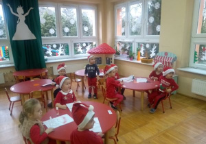 dzieci z grupy II w czerwonych czapkach siedzą przy stolikach