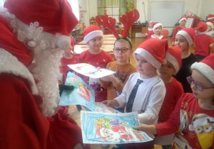 dzieci z gr V wręczają Mikołajowi swoje ilustracje