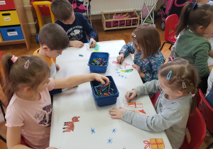 dzieci przy stoliku ozdabiają świąteczny obrus