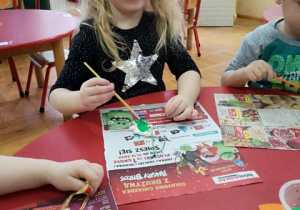 dziewczynka maluje choinkę i uśmiecha się