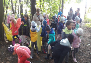 nauczycielki idą za dziećmi z workami a dzieci szukają śmieci