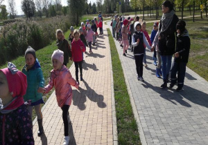 dzieci idą parami ścieżkami nad zalewem