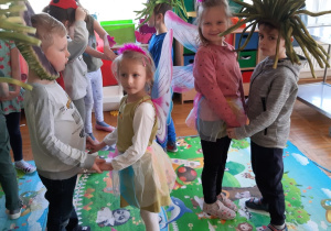 chłopcy - trawy tańczą w parach z dziewczynkami - biedronkami i motylkami