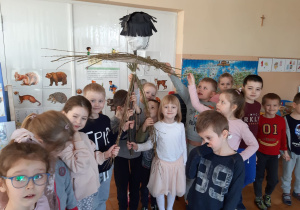 dzieci trzymają konstrukcję przedszkolnej Marzanny wykonanej na patykach z zamocowanymi rękami i nogami z gałęzi