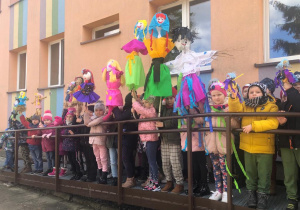 dzieci stoją na rampie przed przedszkolem z Marzannami dużymi i małymi