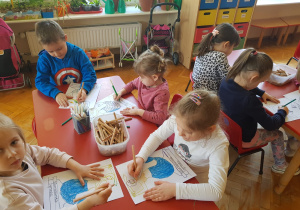 dzieci przy stolikach kolorują rysunek Warszawskiej Syrenki