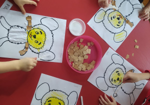 dzieci naklejają kawałki kolorowego papieru na kontur Misia Kudłatka