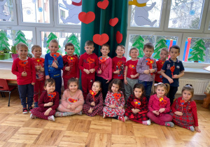dzieci z grupy I z laurkami dla mamy - dużymi, czerwonymi serduszkami na patykach ozdobionymi kolorowymi serduszkami i kokardką z czerwonej wstążki