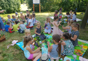dzieci w ogrodzie, na trzech matach, robią bukiety z kwiatów i zbóż