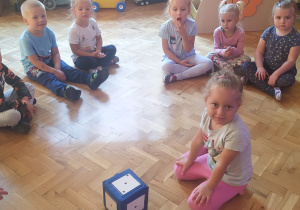 dzieci podczas zabawy z dużą kostką siedzą w kole na podłodze