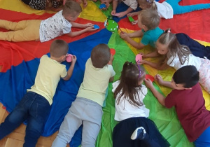 dzieci leżą na brzuchu z kropkami w rękach